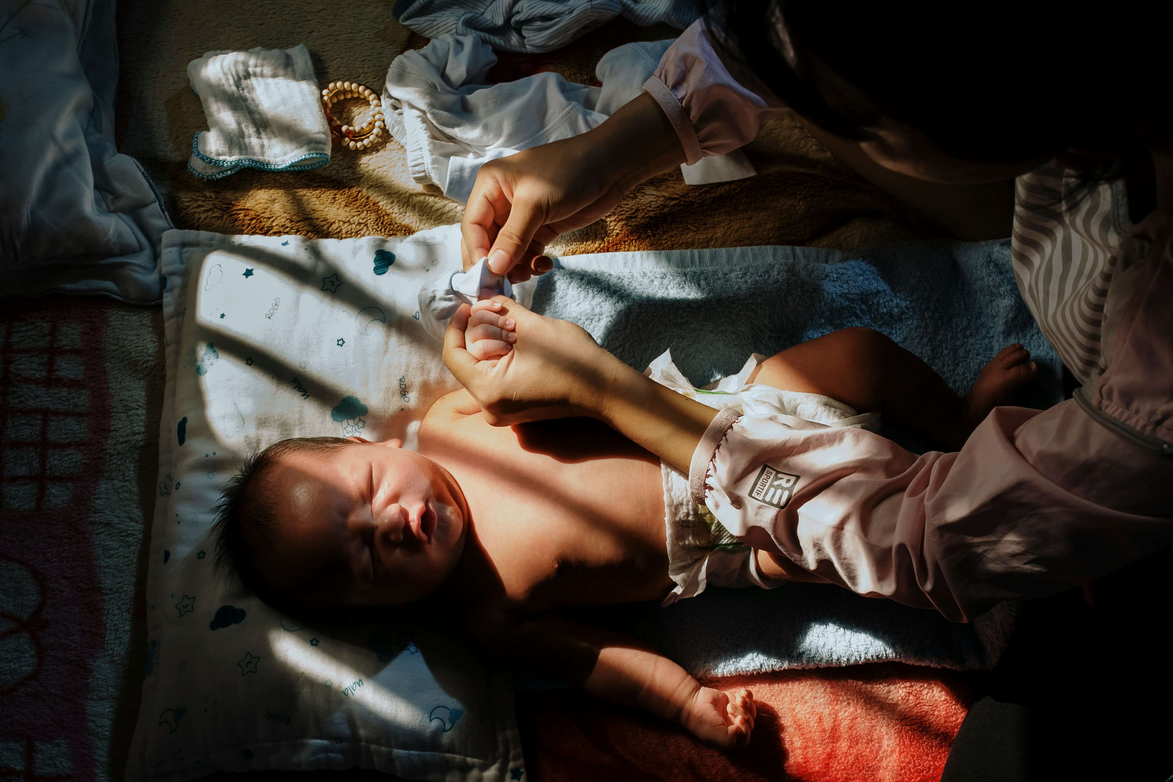 baby lying on bed holding white plastic toy